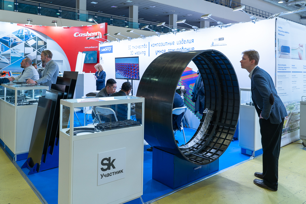 Посетитель выставки «Композит-Экспо 2025» осматривает срез армированной карбоновый трубы повышенной прочности на стенде компании «Карбонтекс»   